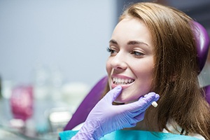 Dentist with purple glove examining patient's smile