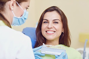 Woman smiling while being shade-matched for dental crown
