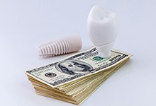 Model of a dental implant in Fort Lauderdale on stack of money