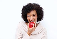 Woman with dental implants in Fort Lauderdale eating an apple