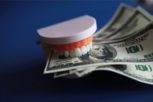 A model jaw biting several dollar bills