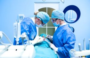 Dental team carefully performing dental implant surgery